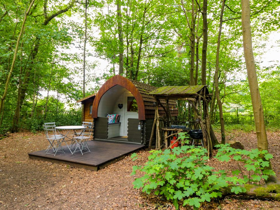 A cabin with a table and chairs outside at Bluebell Glamping Pod in Woolton Hill