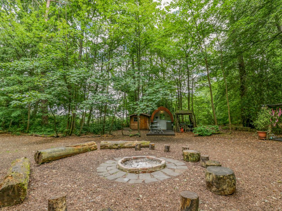 An outdoor area with a fire pit and seating logs at Bluebell Glamping Pod in Woolton Hill