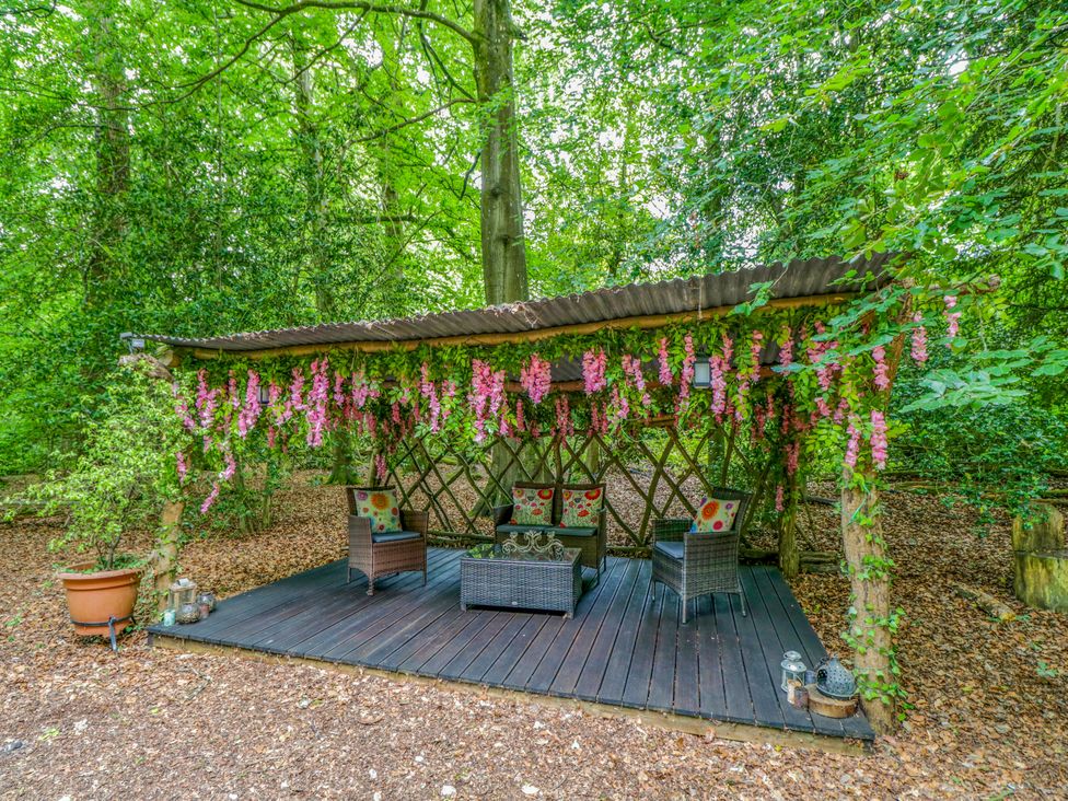 A seating area with a canopy and flowers in a forest at Bluebell Glamping Pod Woolton Hill