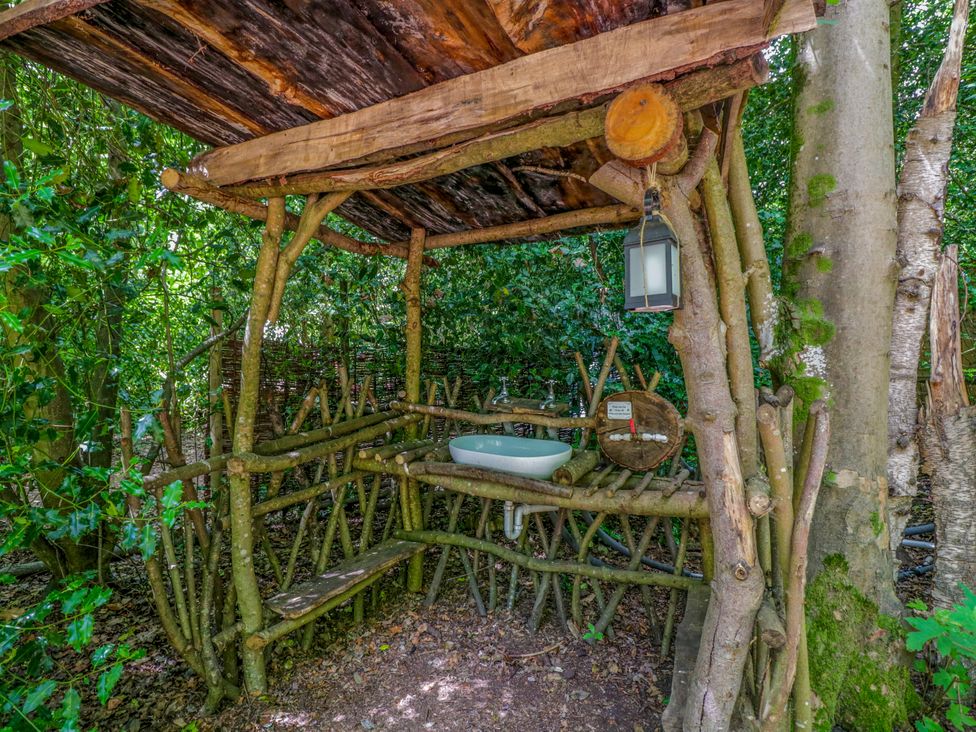 An outdoor wash area with a wooden structure and sink at Bluebell Glamping Pod in Woolton Hill
