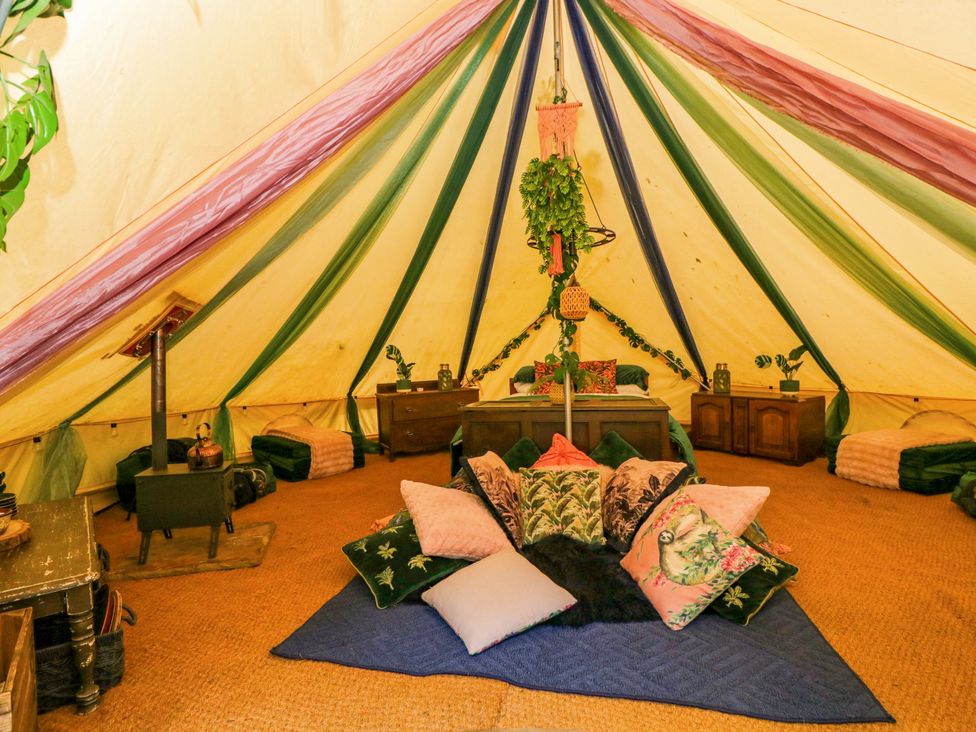 A glamping tent with cushions on the floor at Jungle Bell Tent Woolton Hill