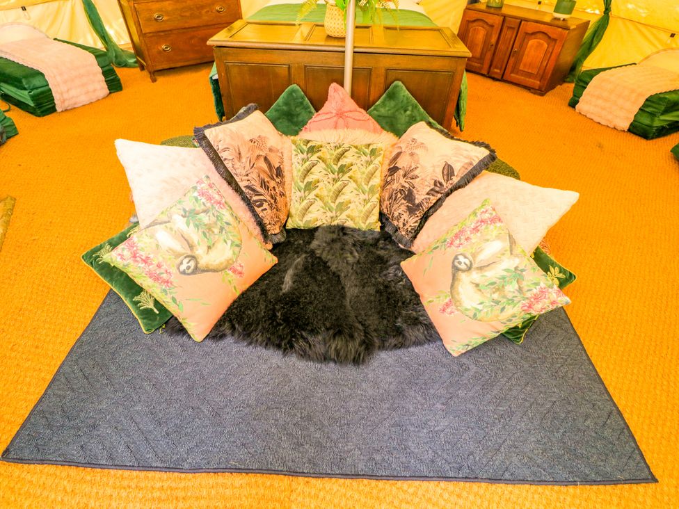A seating area with pillows and a rug at Jungle Bell Tent in Woolton Hill