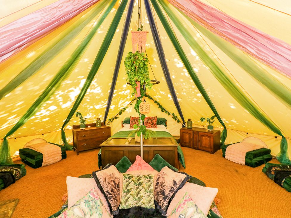 A tent with a bed and cushions at Jungle Bell Tent in Woolton Hill