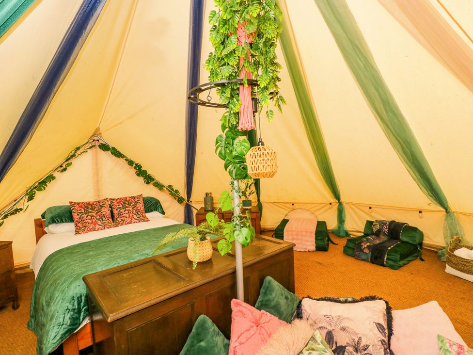 A glamping tent with a bed and decorative items at Jungle Bell Tent in Woolton Hill