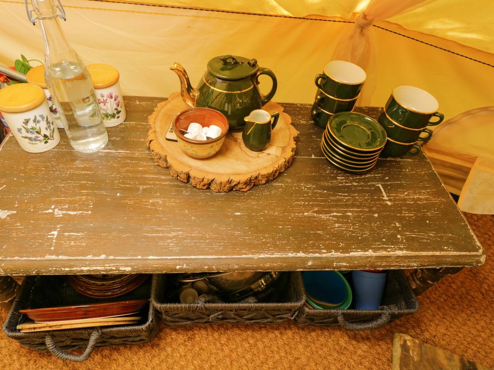 A kitchen table with tea set and storage baskets at Jungle Bell Tent Woolton Hill