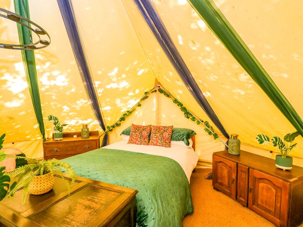 A bedroom with a bed and nightstands at Jungle Bell Tent in Woolton Hill