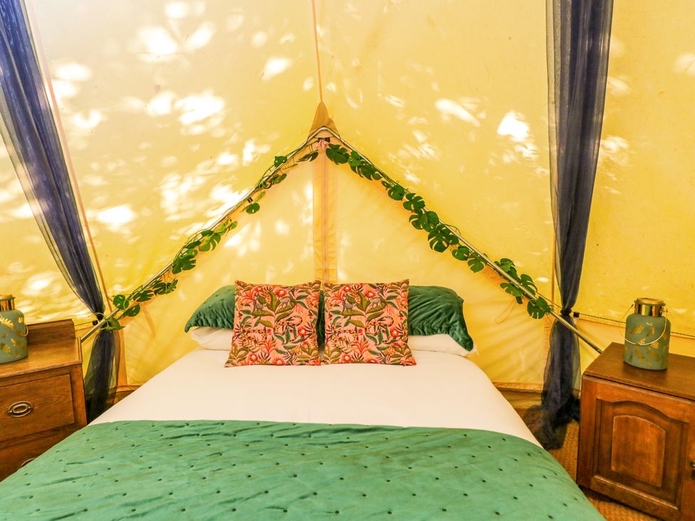A bedroom with a bed and bedside tables at Jungle Bell Tent in Woolton Hill