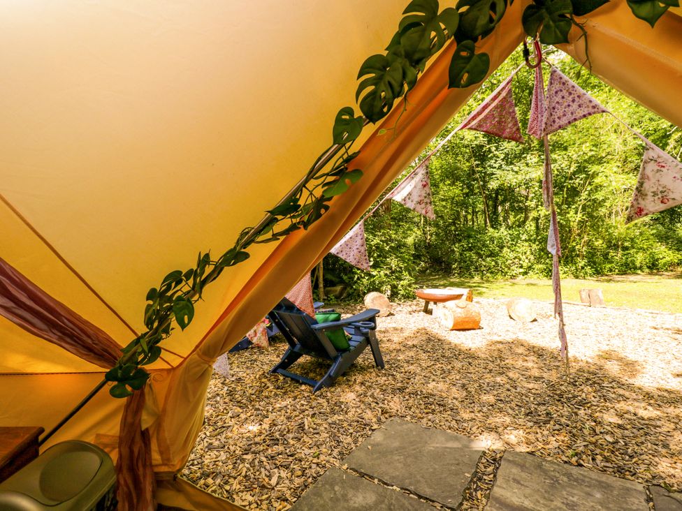 A tent with wooden chairs and decorative bunting at Jungle Bell Tent Woolton Hill