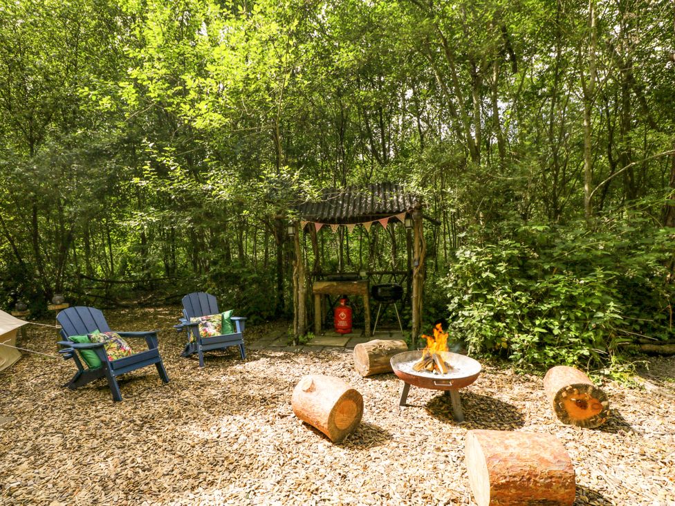 An outdoor area with a fire pit and chairs at Jungle Bell Tent in Woolton Hill