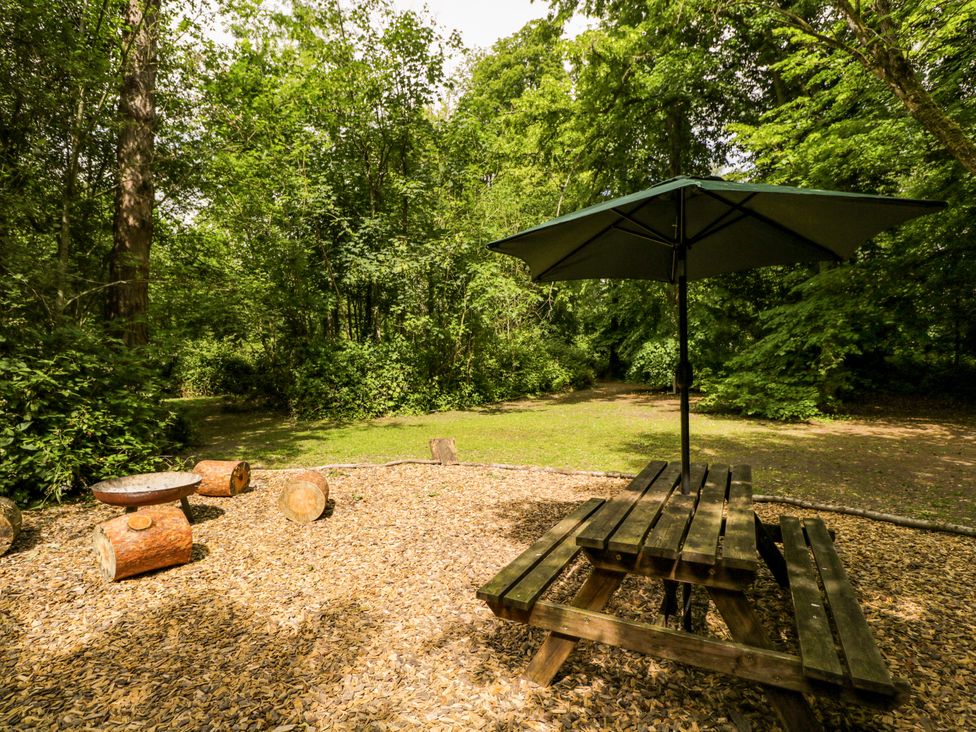 A picnic table with an umbrella in a garden at Jungle Bell Tent in Woolton Hill
