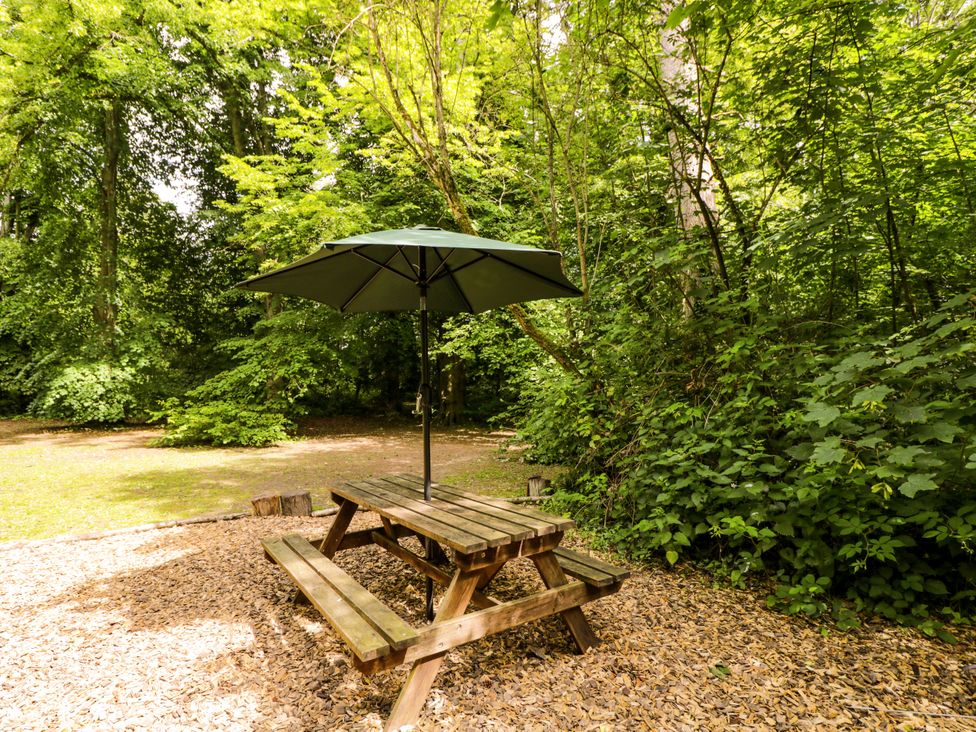 A picnic table with an umbrella in an outdoor area at Jungle Bell Tent in Woolton Hill