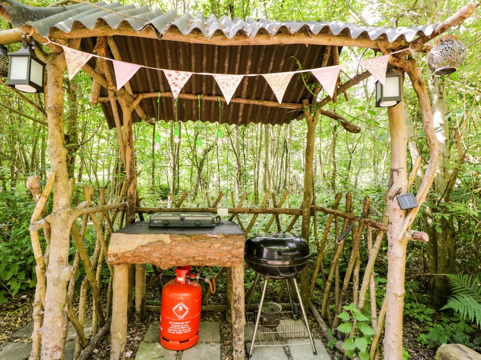 An outdoor cooking area with a camping stove and barbecue grill at Jungle Bell Tent in Woolton Hill