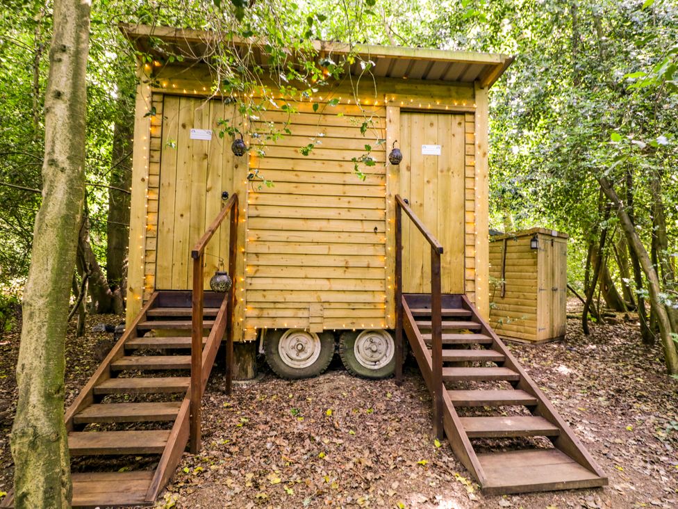 Two wooden structures with steps in a forest at Jungle Bell Tent Woolton Hill
