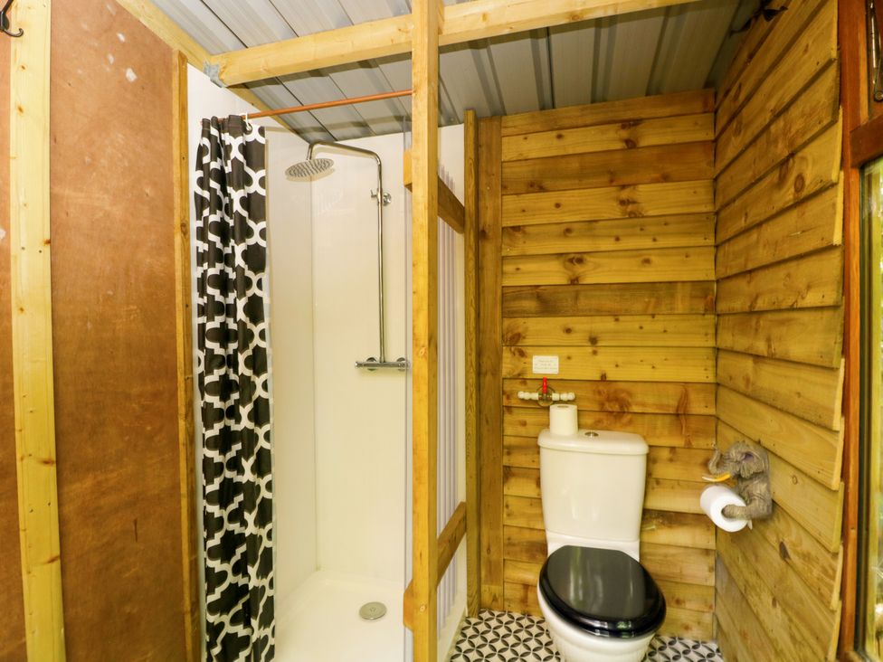 A bathroom with a shower, toilet and sink at Jungle Bell Tent in Woolton Hill