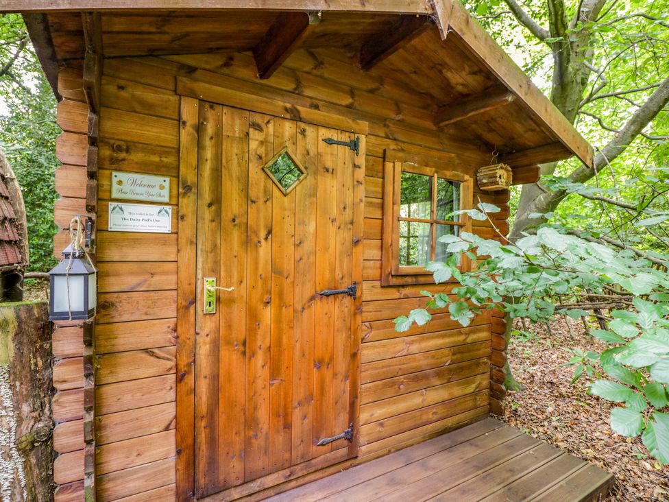 A wooden cabin with a door and window at Jungle Bell Tent in Woolton Hill
