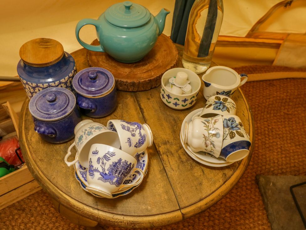 A table with a teapot, tea cups, sugar bowl, and a water bottle at The Moroccan Bell Tent in Woolton Hill