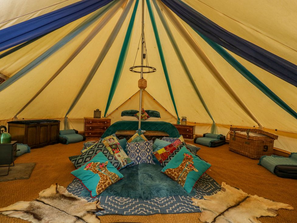 A tent with bed, cushions, and storage at The Moroccan Bell Tent in Woolton Hill