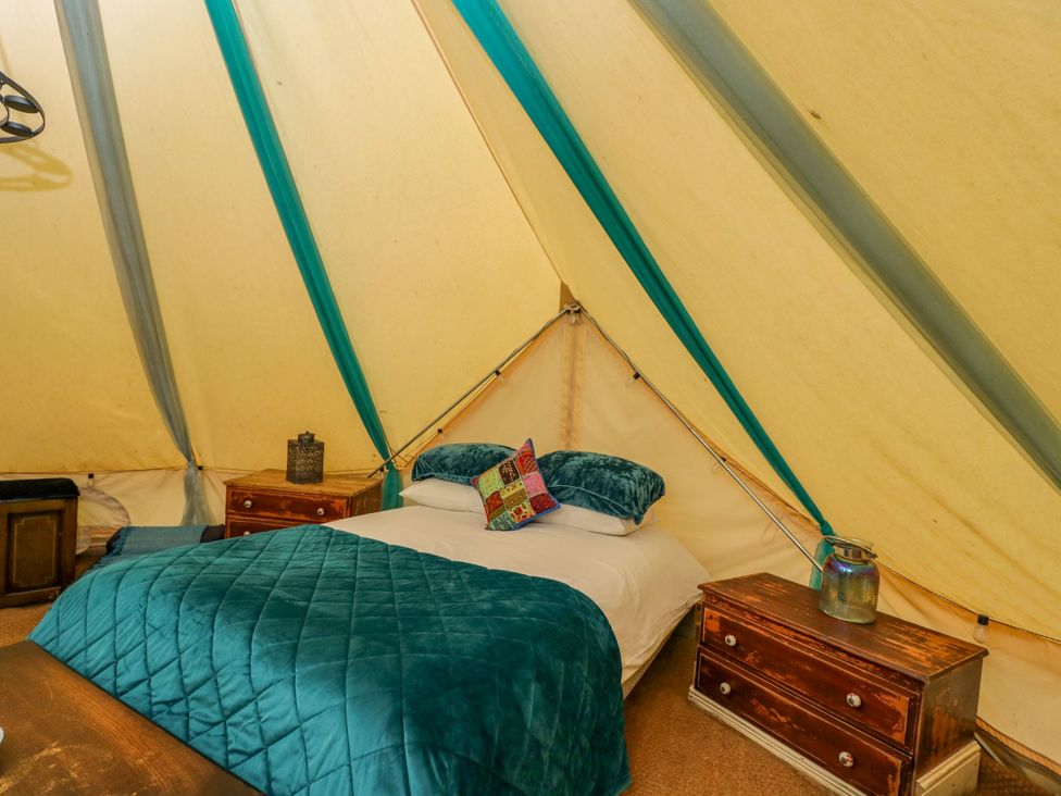 A bedroom with a bed and side tables at The Moroccan Bell Tent in Woolton Hill