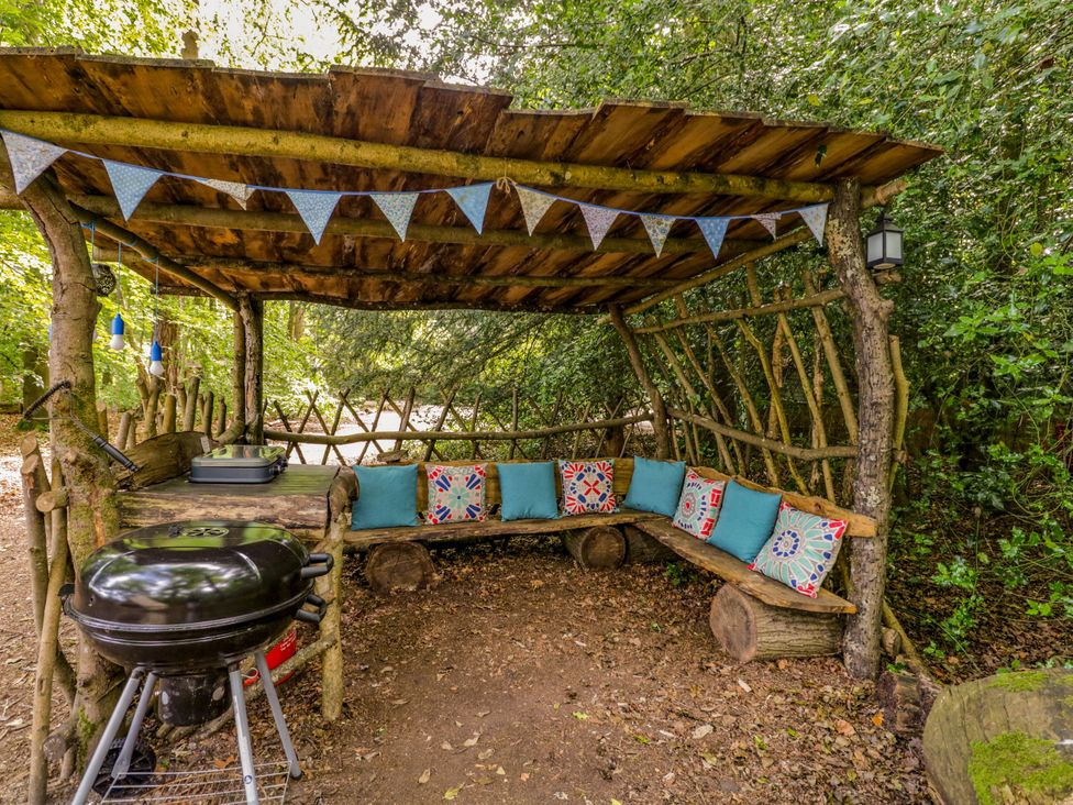 An outdoor seating area with benches and a barbecue at The Moroccan Bell Tent in Woolton Hill
