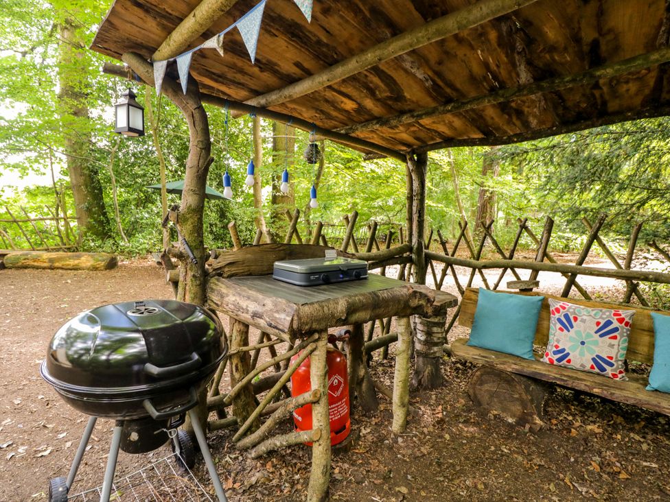 An outdoor area with a wooden table and barbecue grill at The Moroccan Bell Tent in Woolton Hill