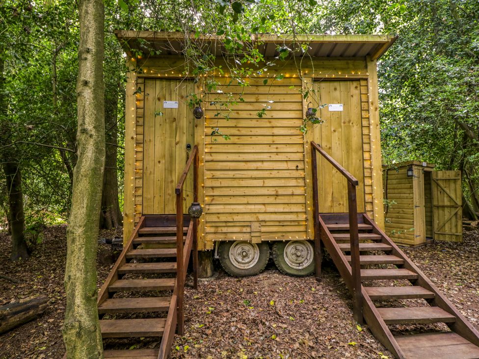 A wooden cabin with stairs and trees around at The Moroccan Bell Tent in Woolton Hill