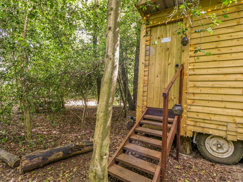 An outdoor wooden structure with stairs and trees around at The Moroccan Bell Tent in Woolton Hill