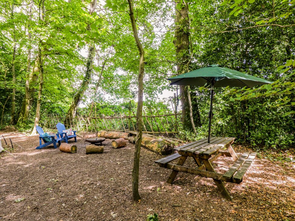 An outdoor seating area with a picnic table and adirondack chairs at The Moroccan Bell Tent in Woolton Hill