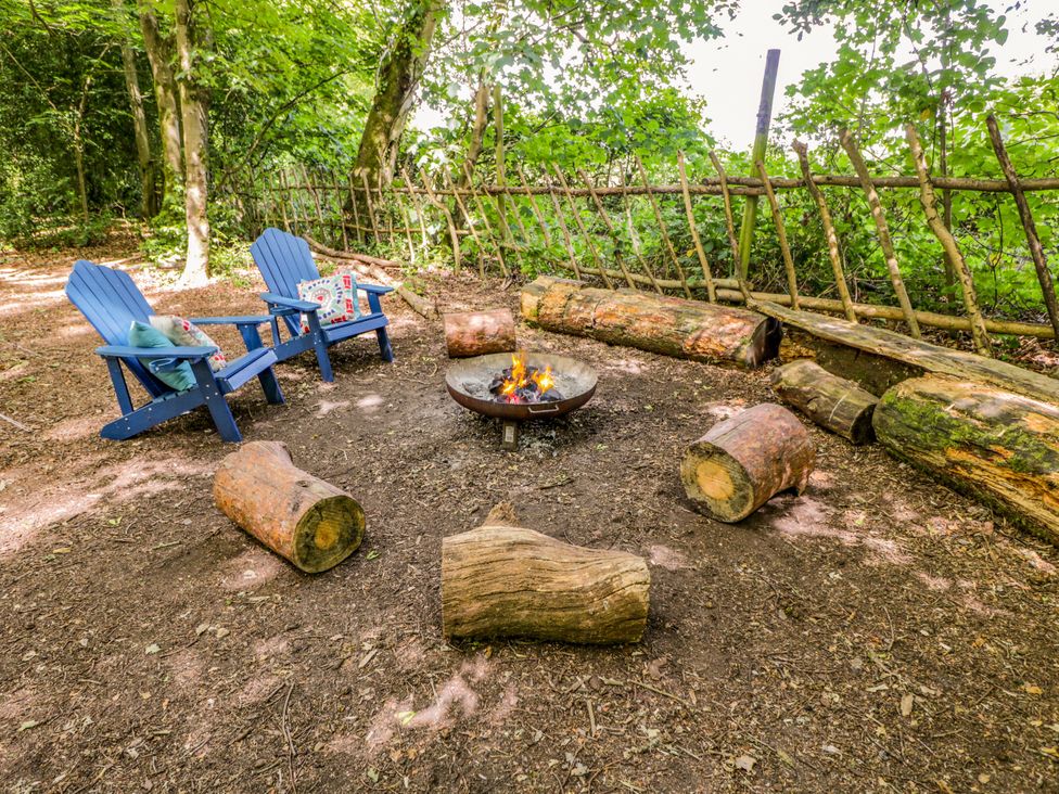 An outdoor seating area with chairs and a fire pit at The Moroccan Bell Tent in Woolton Hill