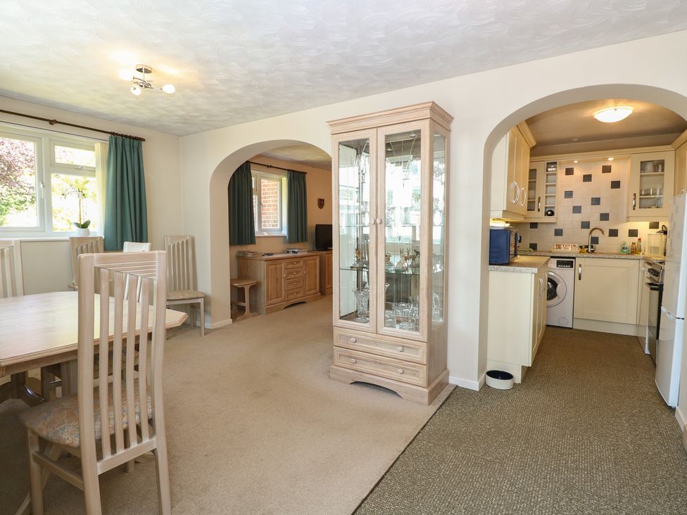 A dining room with a table and display cabinet at 51 Colin McLean Road in Dereham
