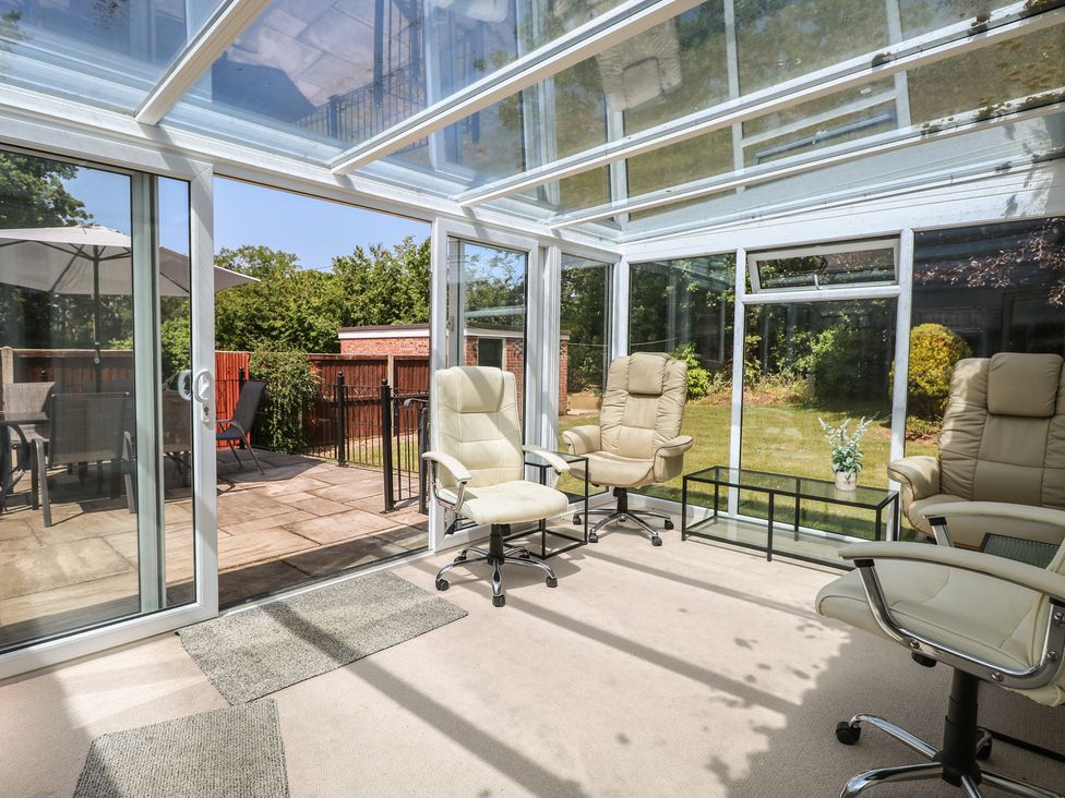 A conservatory with seating area and glass doors at 51 Colin McLean Road Dereham