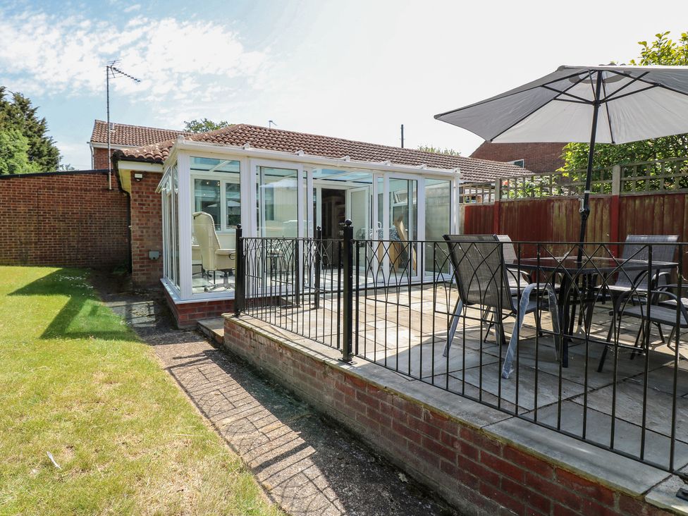 A garden with a conservatory and seating area at 51 Colin McLean Road Dereham