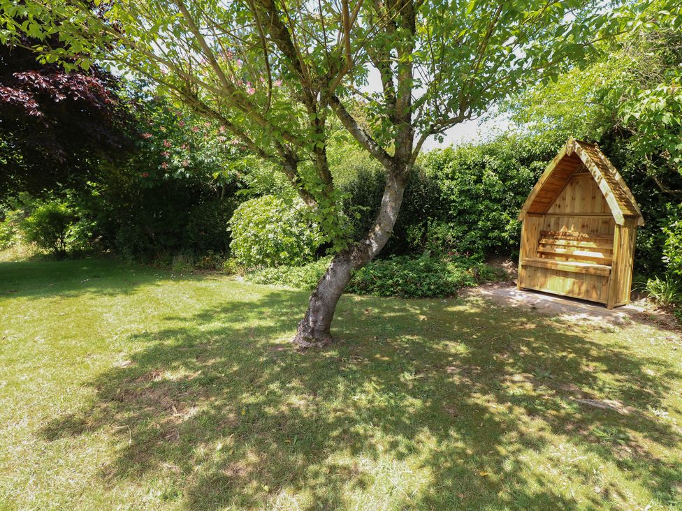 A garden area with a tree and a wooden bench at 51 Colin McLean Road Dereham