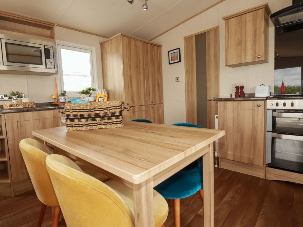 A kitchen with wooden cabinets and a table with chairs at CC2