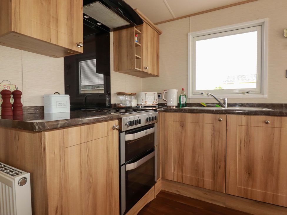 A kitchen with cabinets, stove, sink, and utensils at CC2 