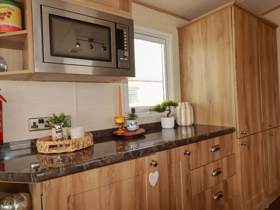 A kitchen with a microwave and wood cabinets at CC2