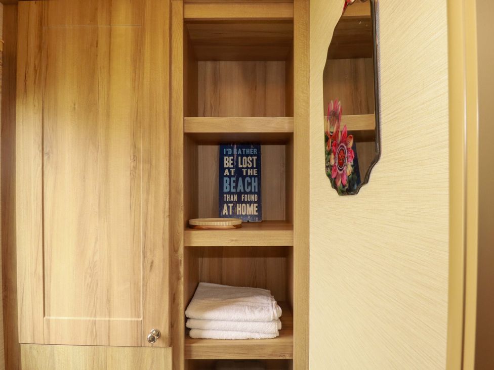 A wooden cabinet with shelves and towels in a bathroom at CC2