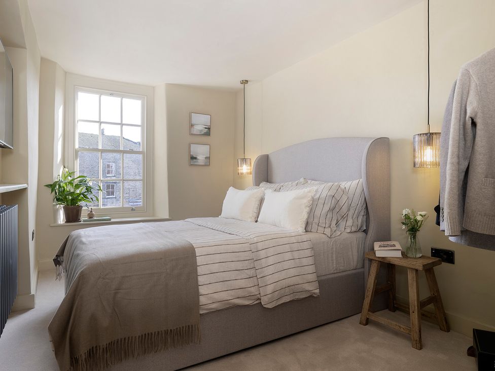 A bedroom with a bed, bedside table, and plant at Church Alley House Stow-On-The-Wold