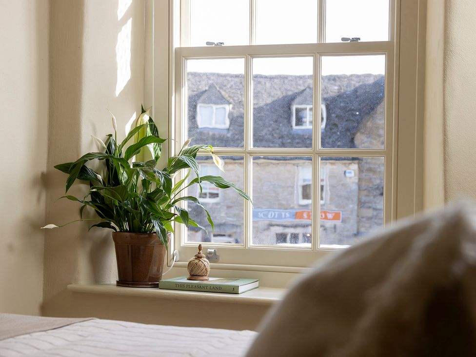 A bedroom window with a plant and a book at Church Alley House Stow-On-The-Wold