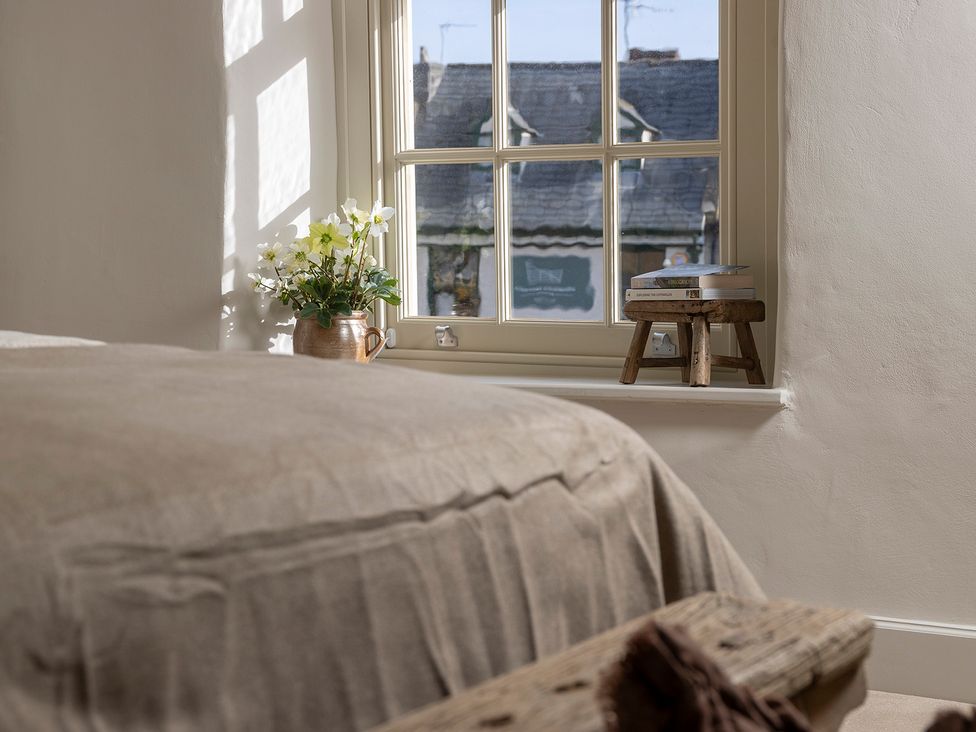 A bedroom with a window and a stool with books at Church Alley House Stow-On-The-Wold