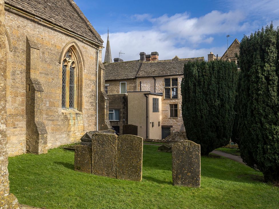An outdoor view of a church with gravestones and buildings at Church Alley House in Stow-On-The-Wold
