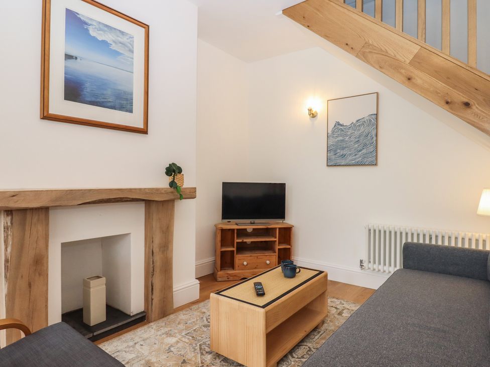 A living room with a TV and fireplace at Hares Cottage in Torquay