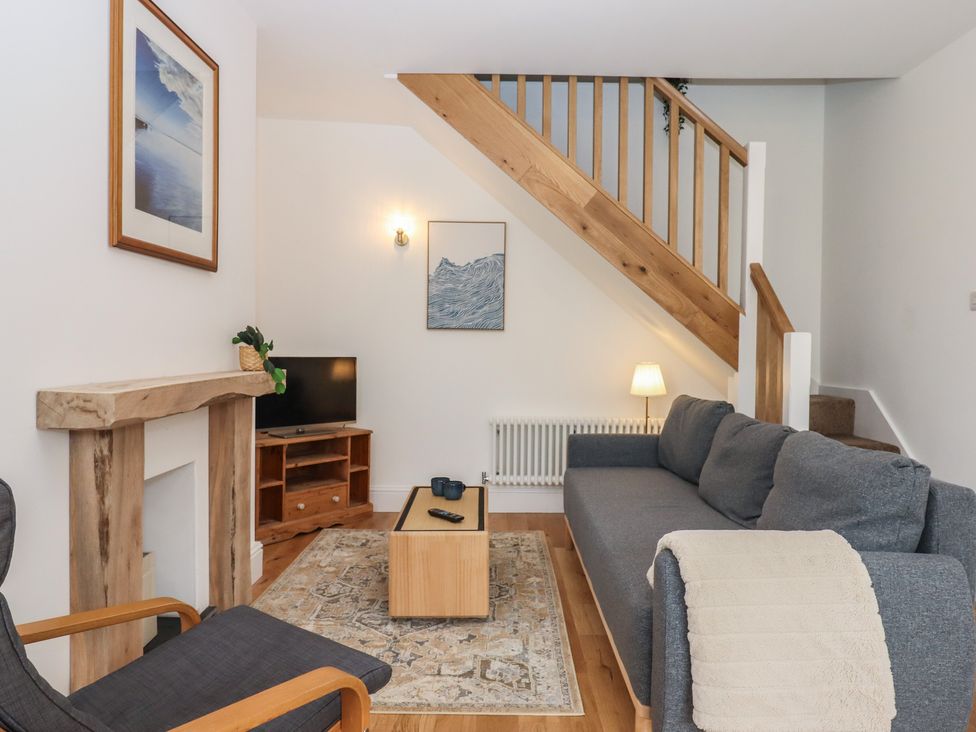 A living room with a sofa and television at Hares Cottage in Torquay