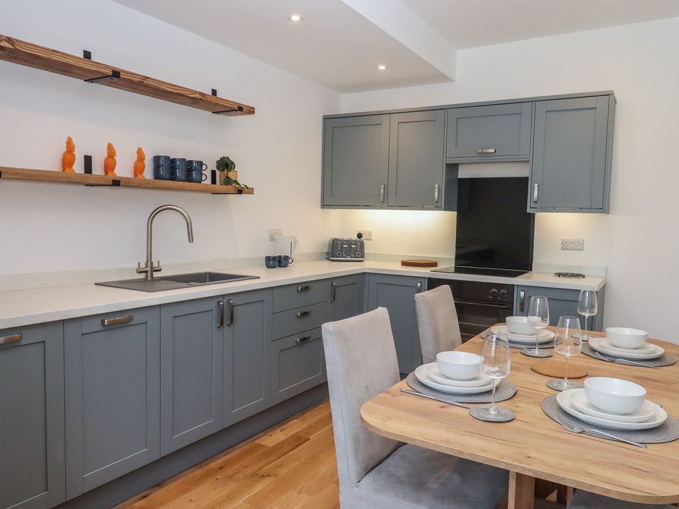 A kitchen with a dining area featuring a table set for meals at Hares Cottage in Torquay
