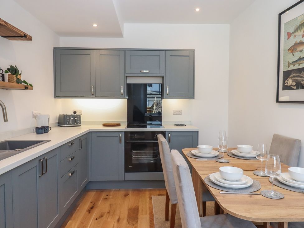 A kitchen with cabinets and dining table at Hares Cottage in Torquay