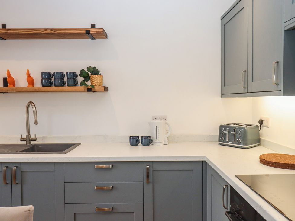 A kitchen with a sink, cabinets and various small appliances at Hares Cottage in Torquay
