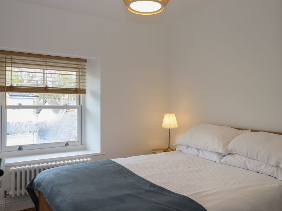 A bedroom with a bed and lamp at Hares Cottage in Torquay