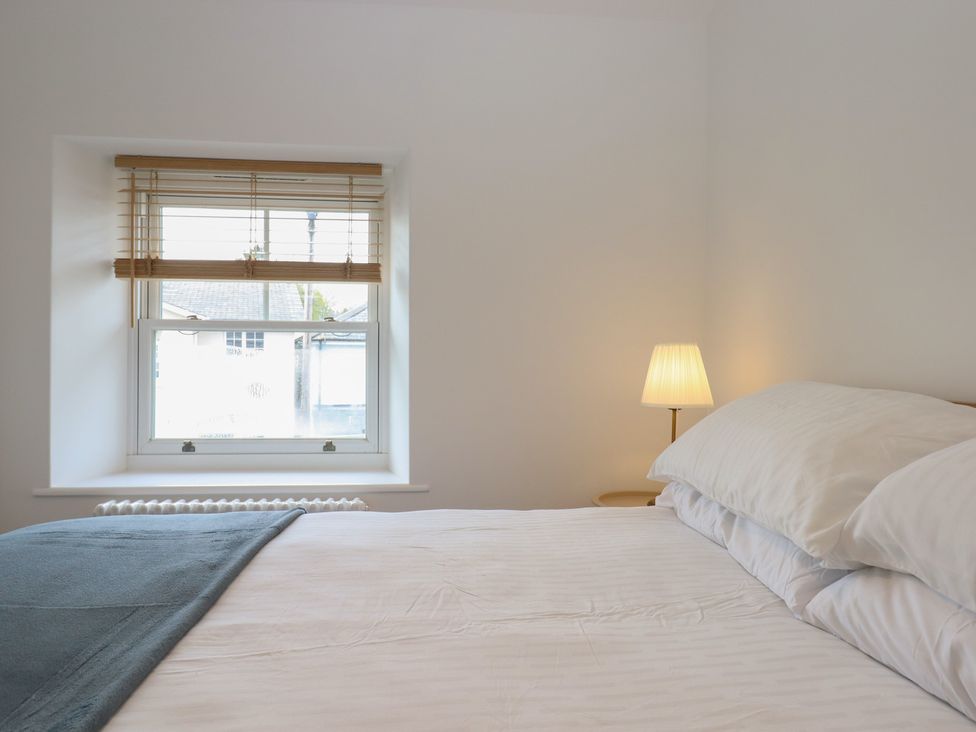 A bedroom with a bed and a lamp at Hares Cottage in Torquay