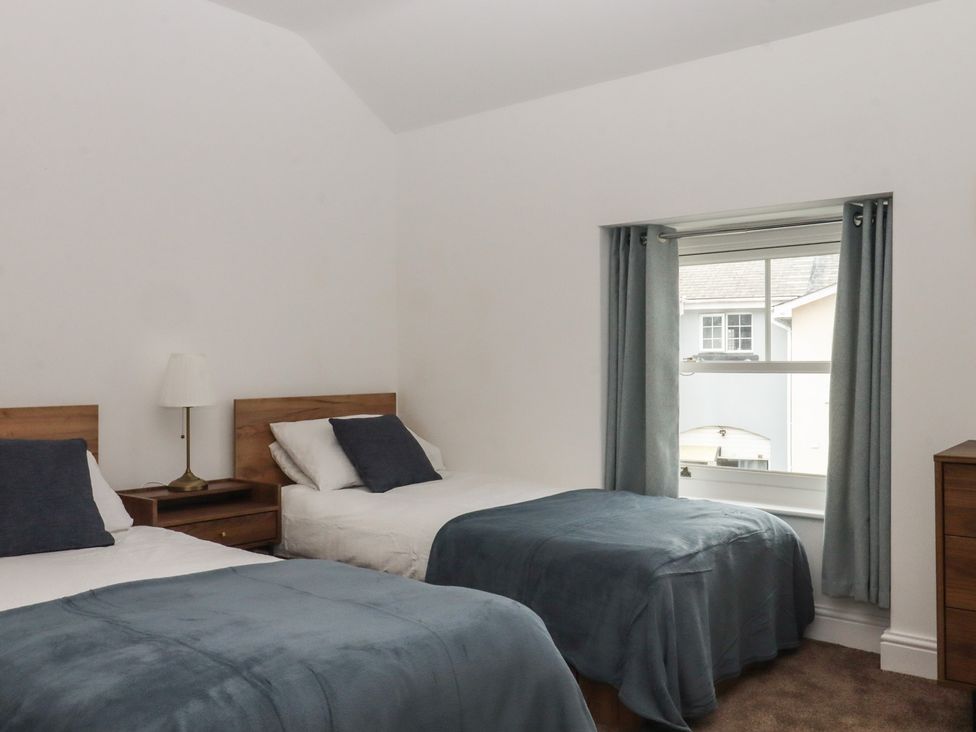 A bedroom with two beds and a window at Hares Cottage in Torquay