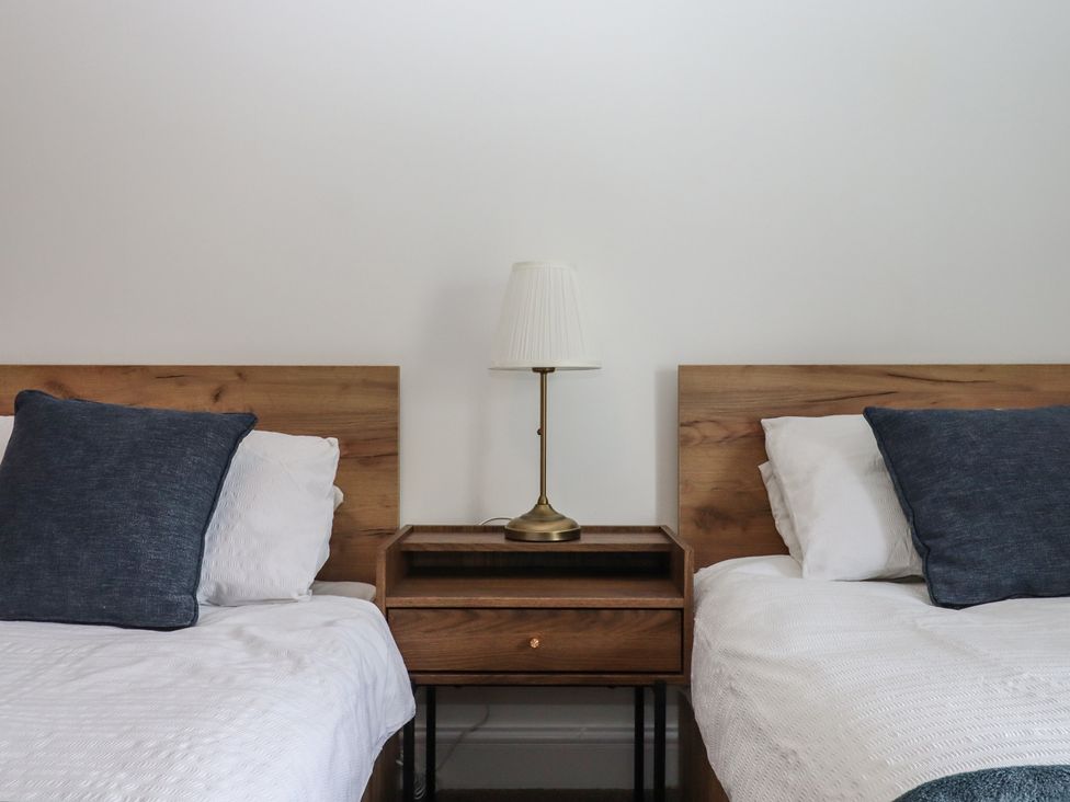 A bedroom with two beds and a nightstand at Hares Cottage in Torquay