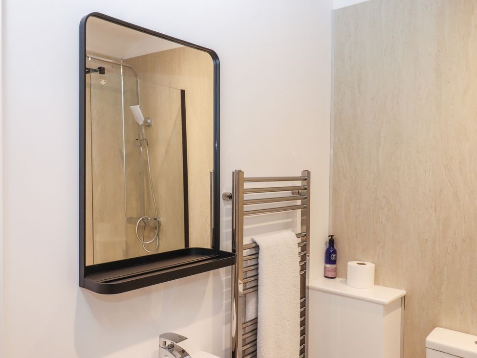 A bathroom with a shower and towel rail at Hares Cottage in Torquay